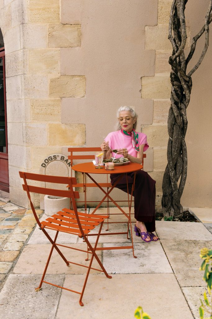 Table et chaises pliantes Bistro de Fermob couleur orange sur une terrasse en pierre