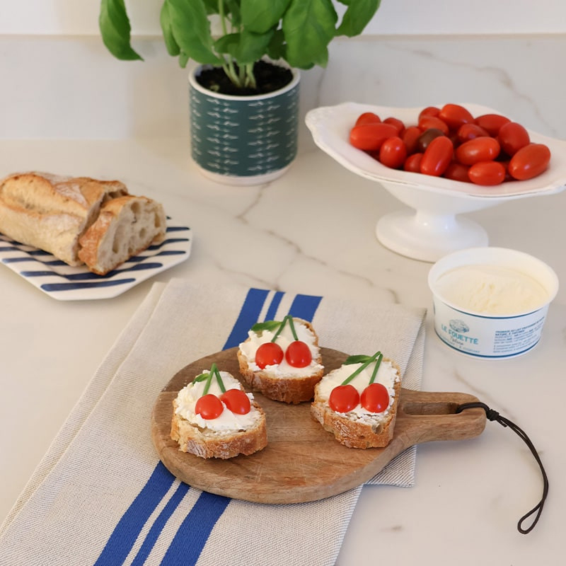 Torchon basque blanc à rayures bleues sous une planche apéritive